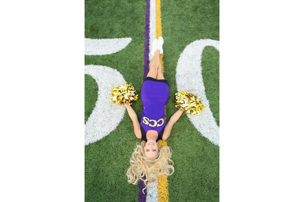 high school cheerleader posing on the 50 yard line for senior cheer pics