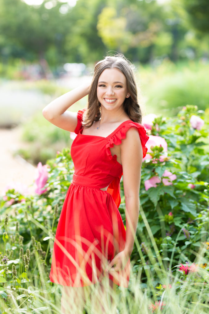 senior girl in a dress and flowers posing for her senior pictures