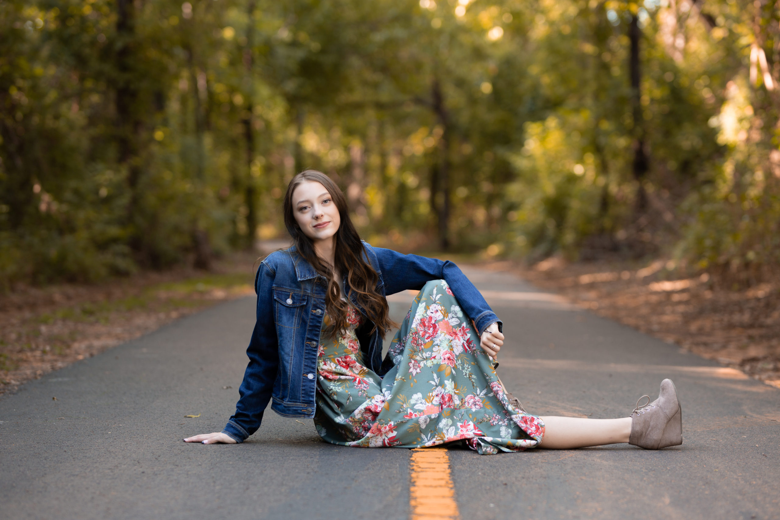 senior girl sitting on walking trail smiling for camera
