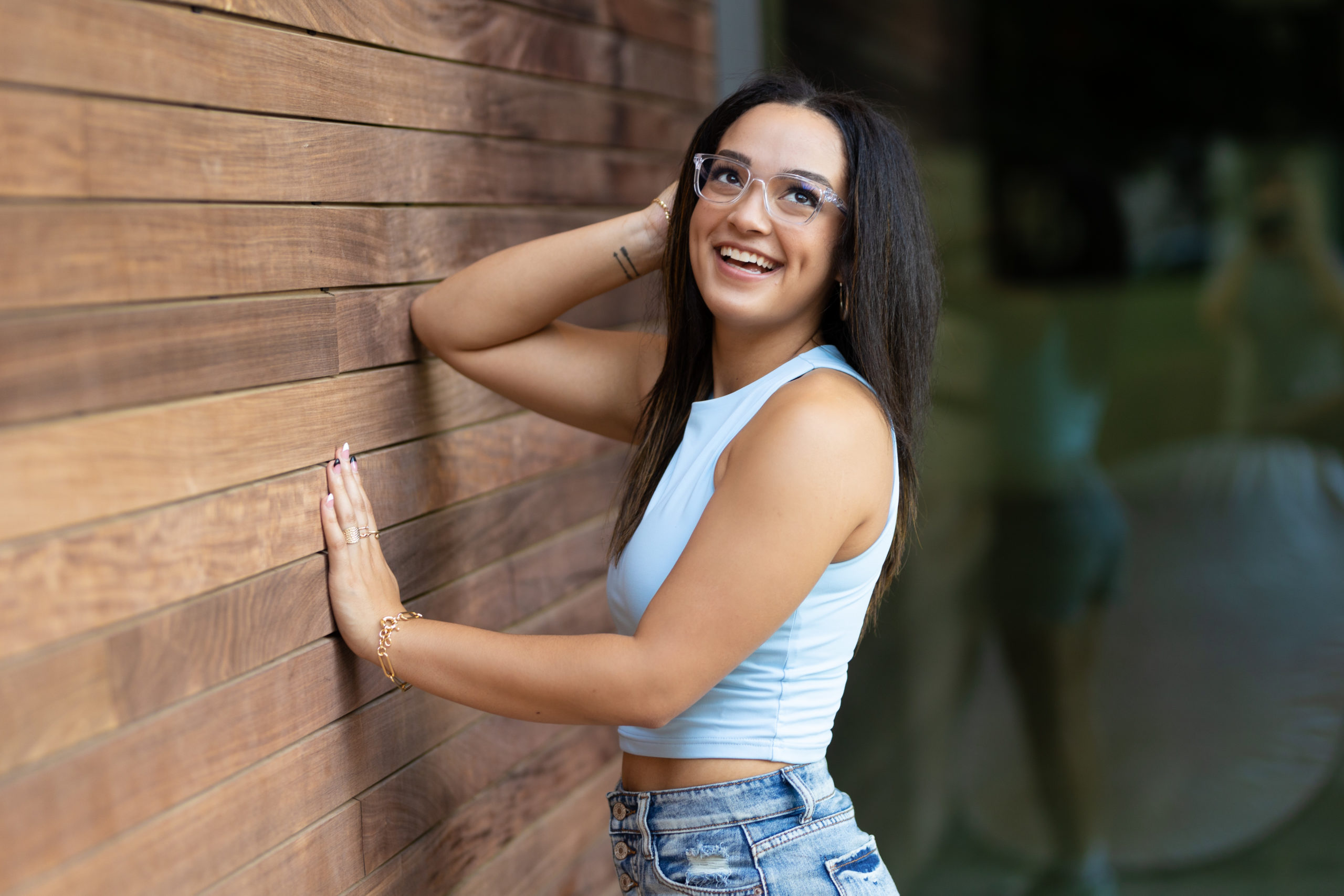 oklahoma senior girl posing in front of wooden wall for senior photos