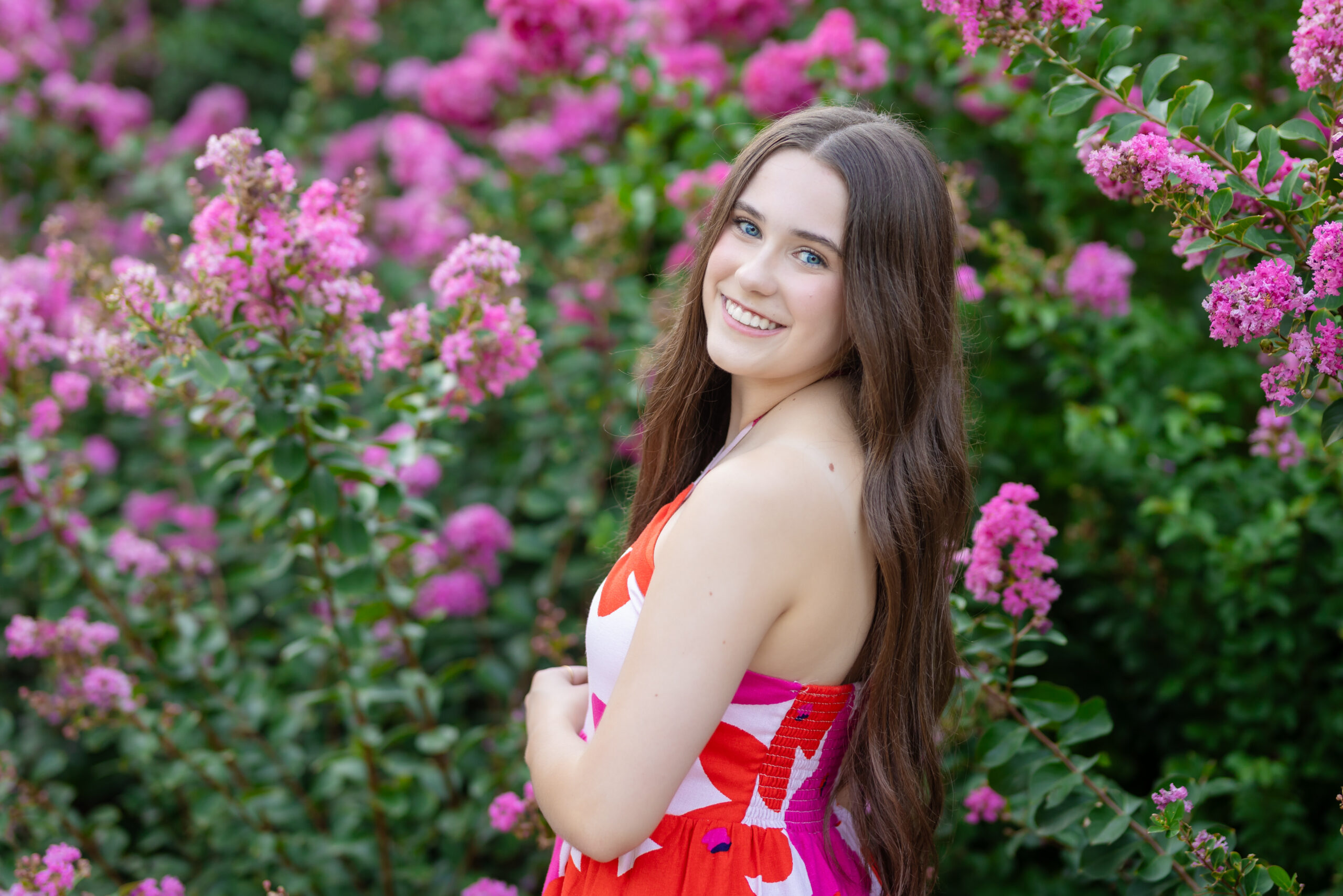 senior girl posing in pink flowers in downtown OKC for her senior pictures