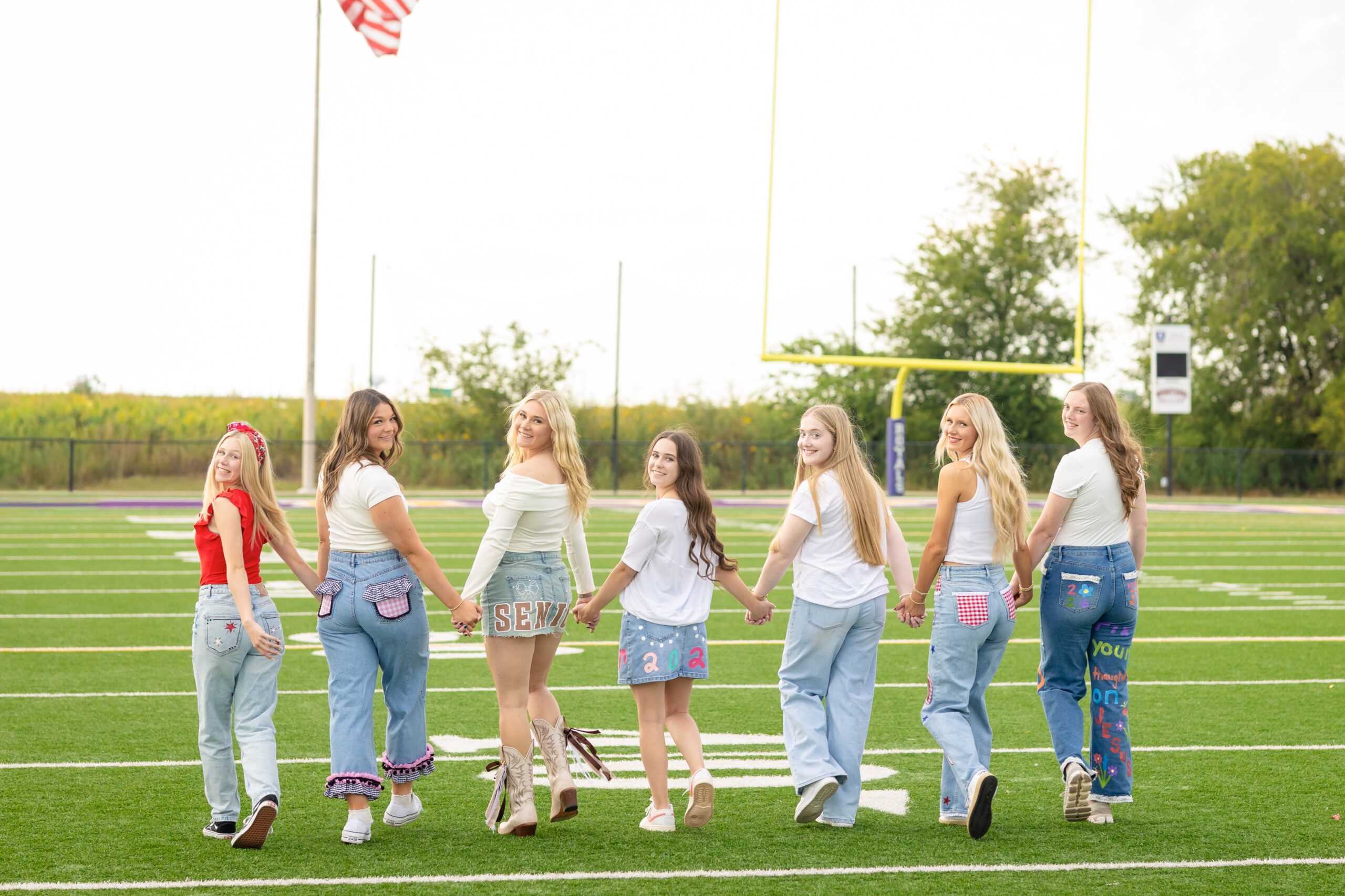 senior girls posing in their senior jeans on a high school football field in norman, oklahoma